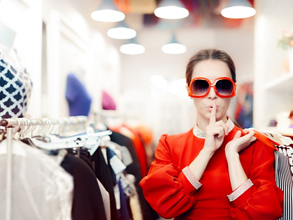 Woman in a clothes store wearing sunglasses and keeping her identity secret